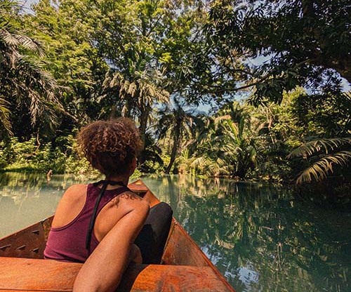 Canoe gliding across a border lake near Kilimanjaro with forest along the shoreline